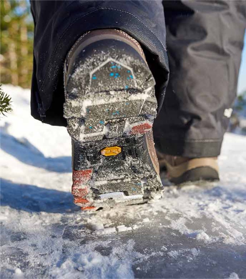 Person walking across wet, icy lake in boots with Arctic Grip.