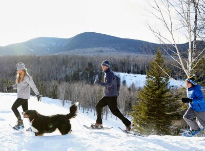 A family snowshoeing with their dog.