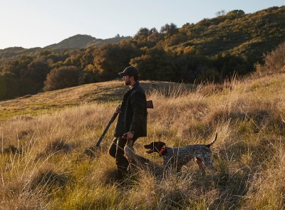 A hunter walking in a field.