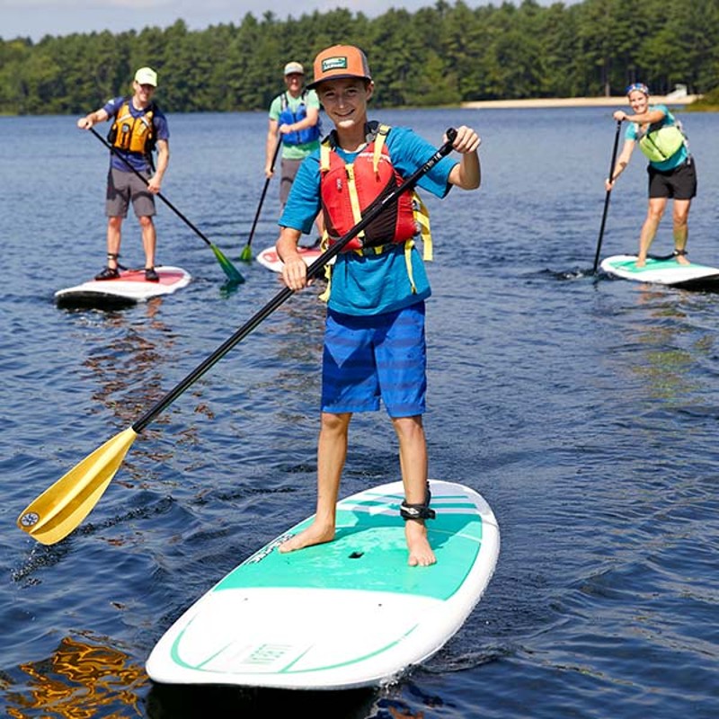 Kayak with two people skimming over shimmering blue water