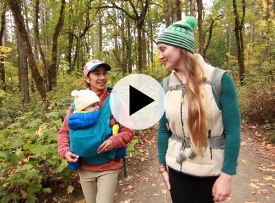 Two women walking. One woman has baby in a front backpack.