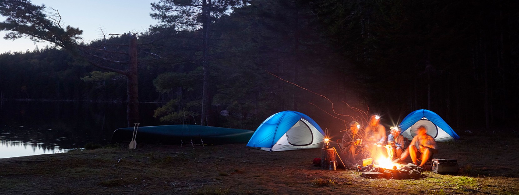 Family gathered around campfire at night.