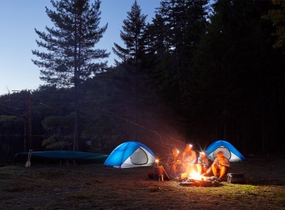 A family gathered around a campfire at their campsite.