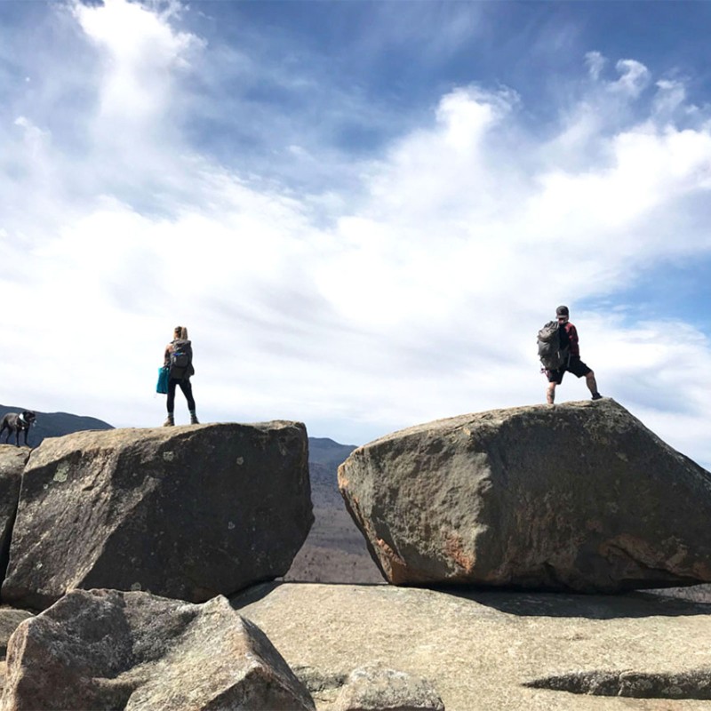 2 hikers atop separate boulders enjoying the view.