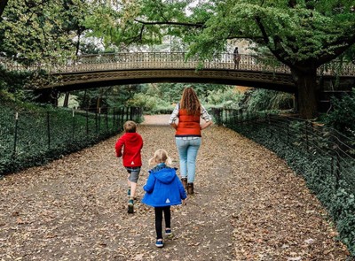 Mom and kids walking down leaf covered walkway.