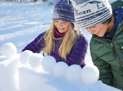 Two children building a snow fort.