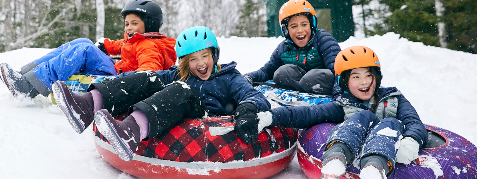 Happy children with helmets sledding in Sonic Snow Tubes.