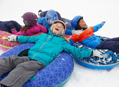 Laughing children sliding on L.L. Bean Sonic Snowtubes.