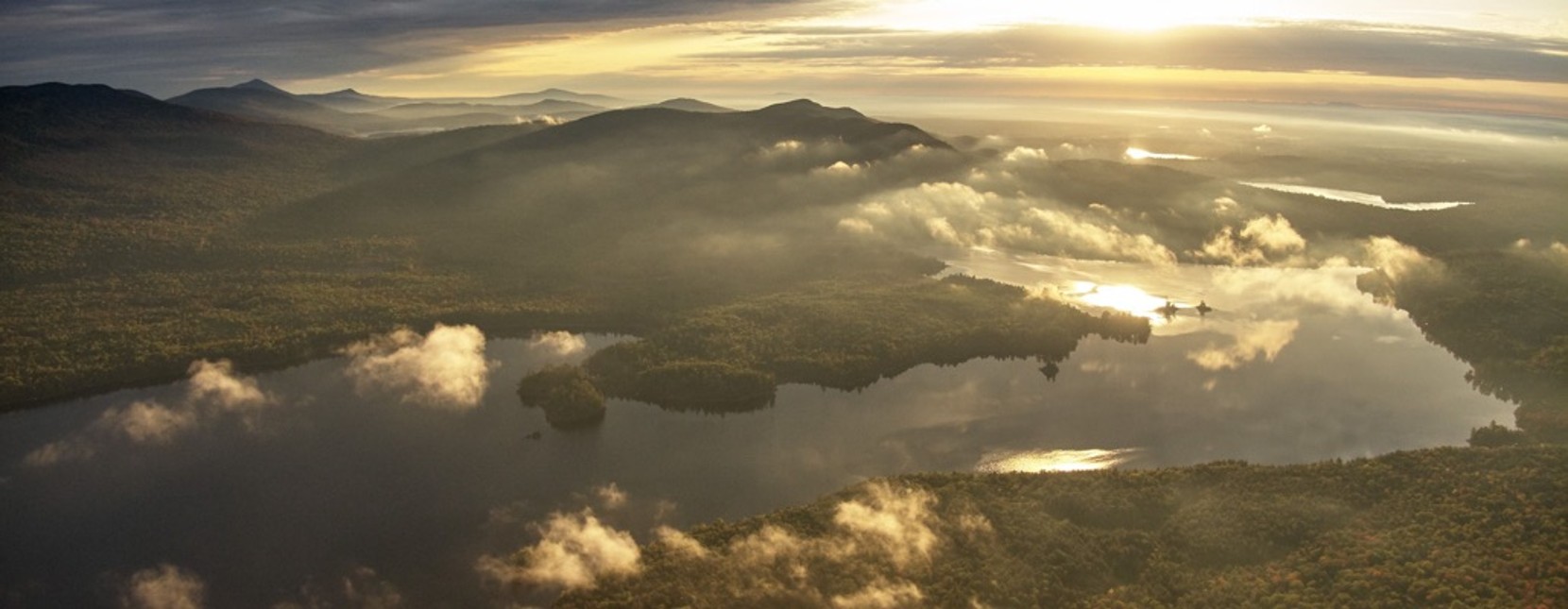 Beautiful mountains and lakes shown from above the few clouds in the sky.