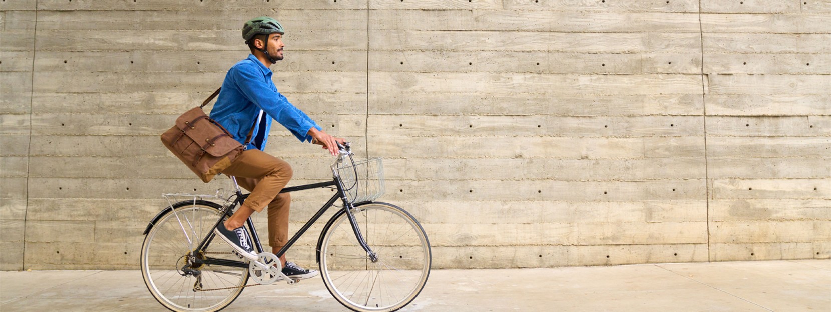 Man commuting by bicycle in the city carrying a messenger bag.