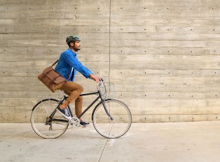 A man riding a bike in the city carrying a messenger bag.