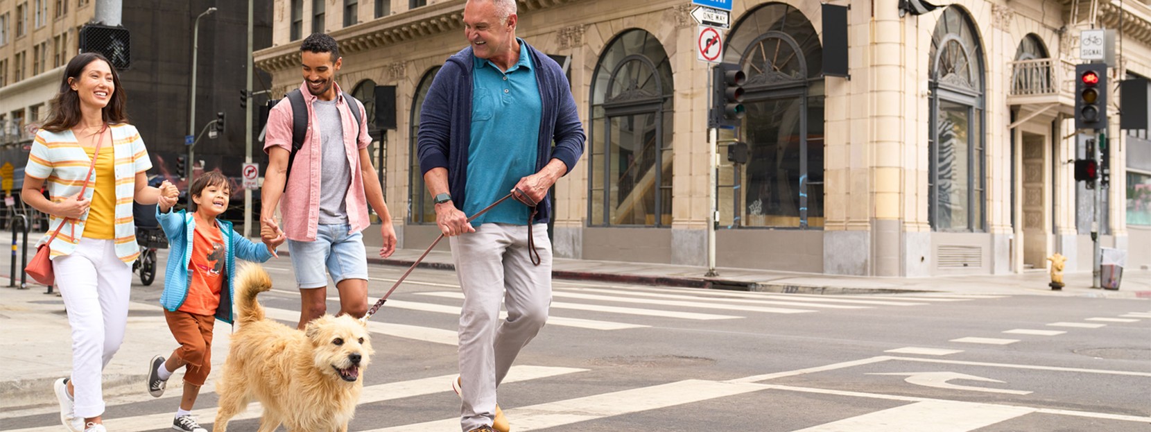 Family of four walking their dog in the city.