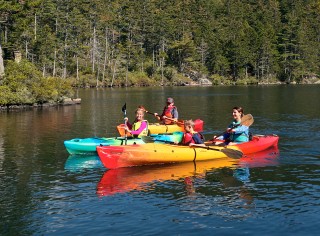 Family of 4 kayaking on a lake