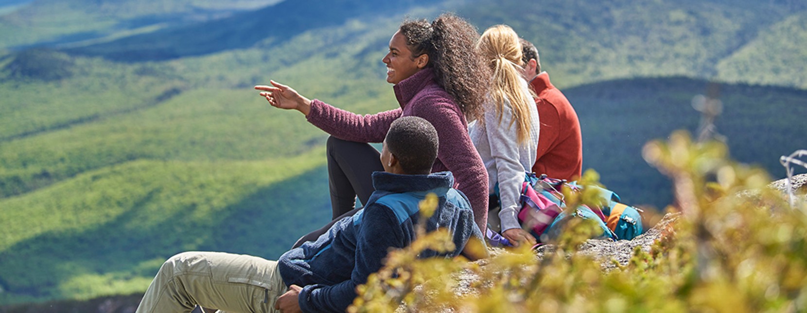 Group of people sitting, looking out over a mountain landscape
