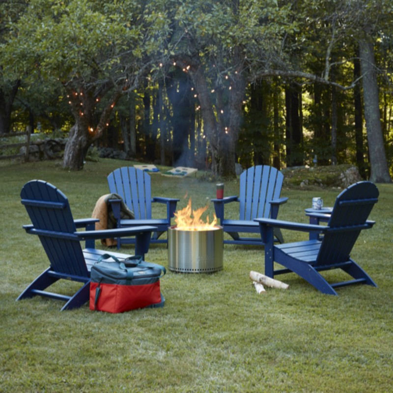 4 blue adirondack chairs in a back yard around a firepit.