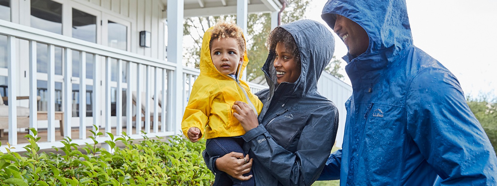 Family standing in the rain smiling.