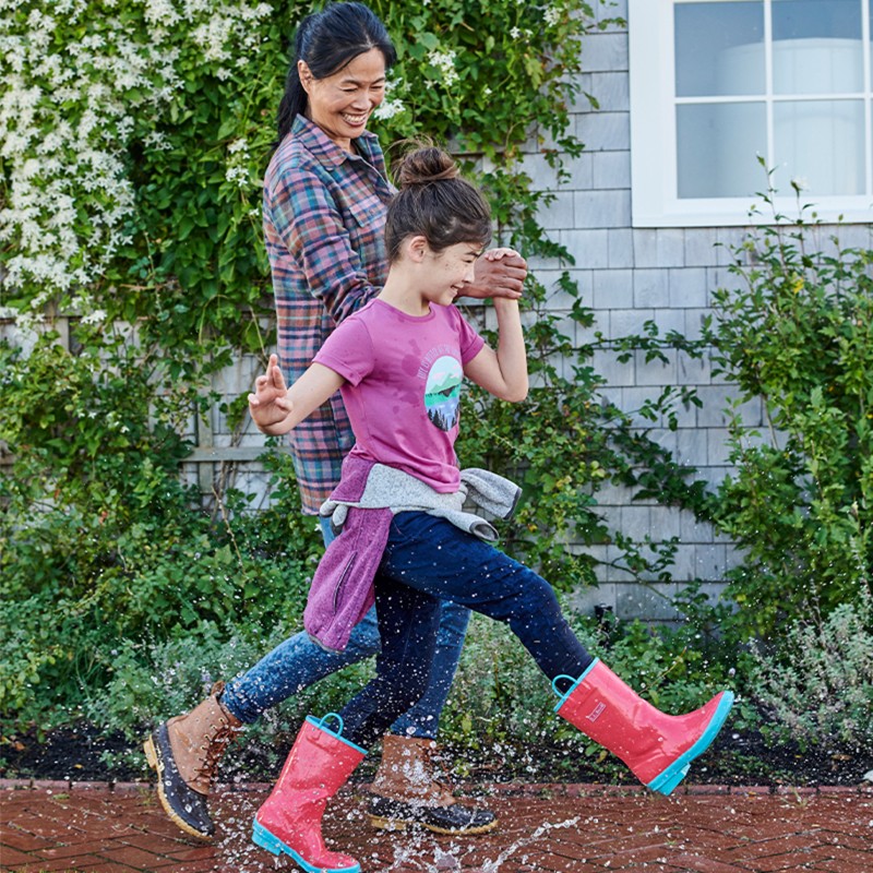 Mother and daughter stomping in rain puddles