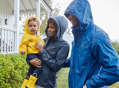 Family standing in the rain smiling.