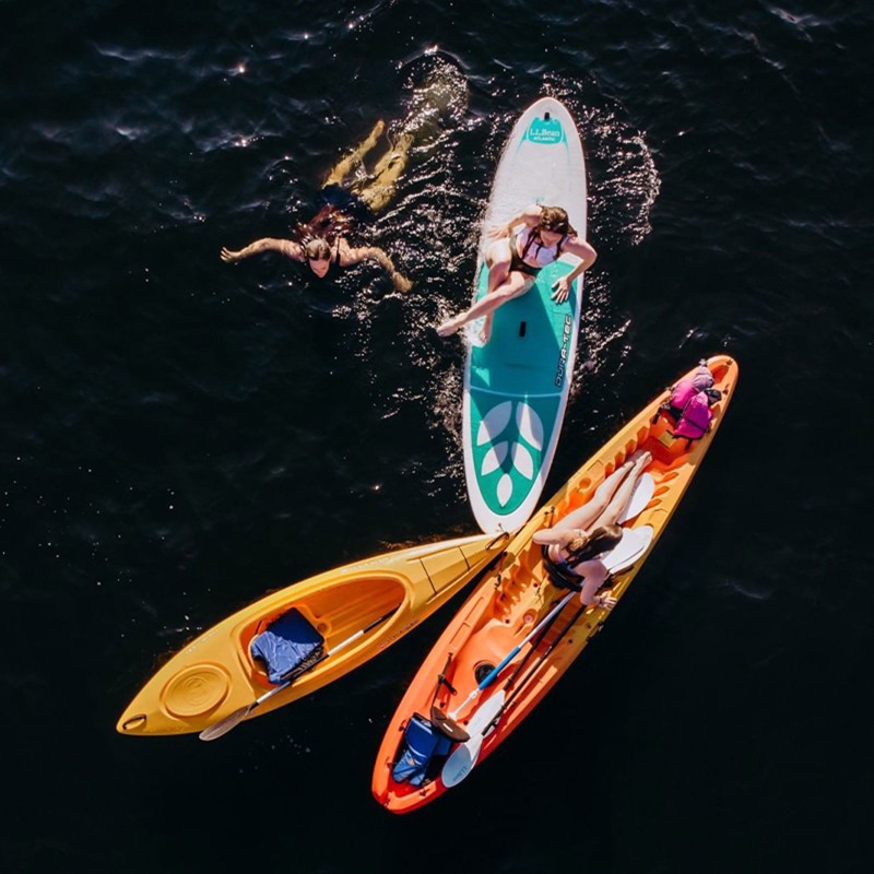 Three friends on the water, 2 in kayaks and 1 on a stand-up paddleboard.