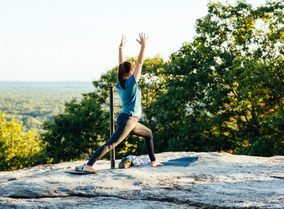 A woman standing on top of a flat top mountain in a yoga pose.