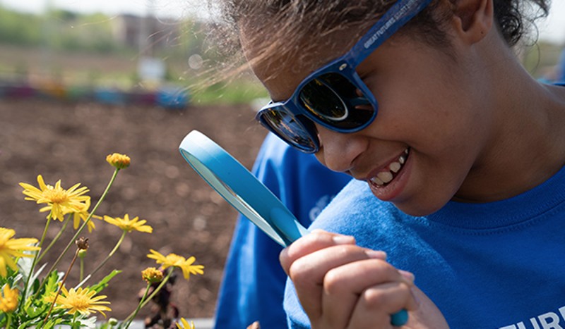 Girl looking a flower with magnifying glass