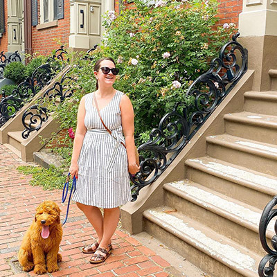 Photo of a woman walking down her city steps with a dog.