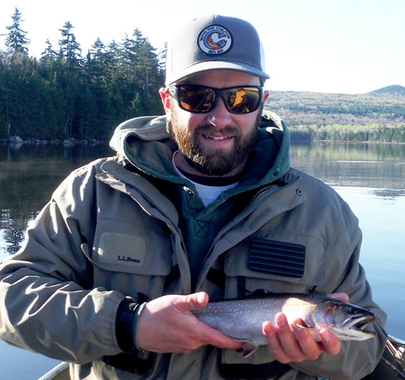 Casey Mealey sitting in a boat holding a fish.