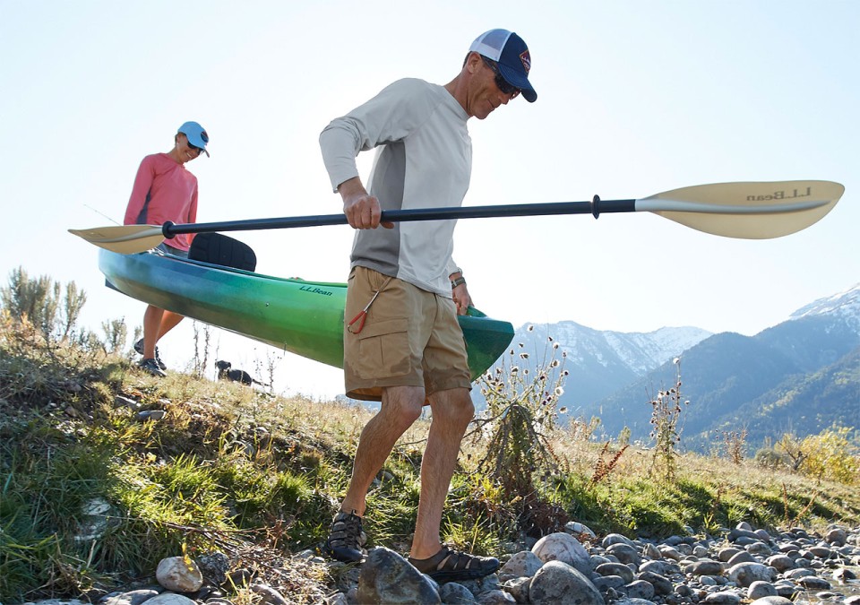 2 men carrying a kayak to the water.