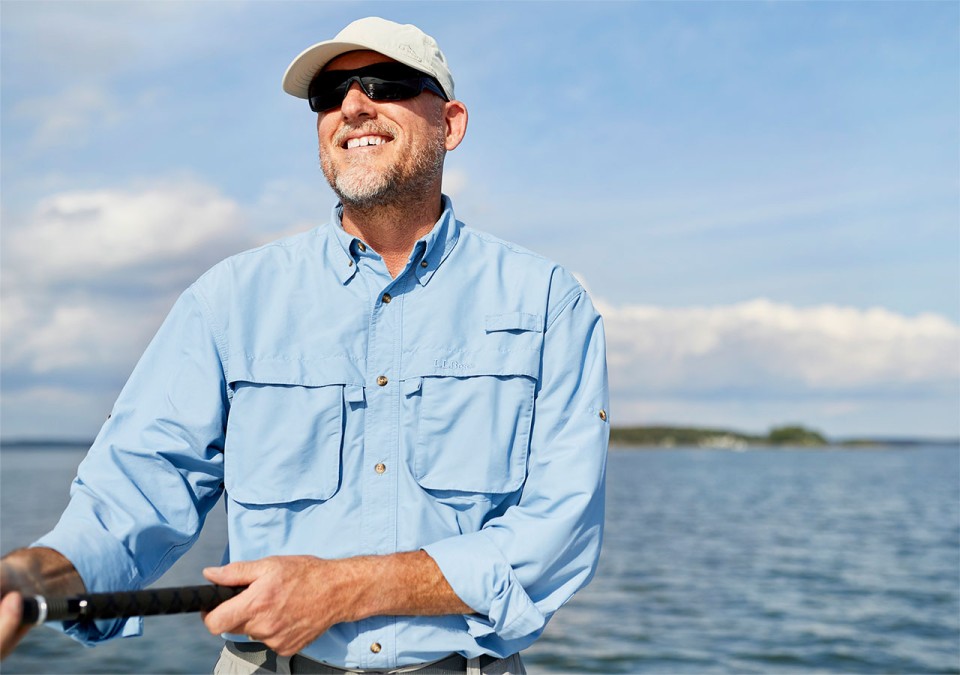 Man standing in a boat fishing wearing a SunSmart shirt.