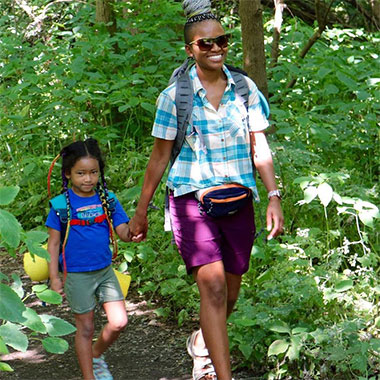 A mom and girl holding hands on a hike.