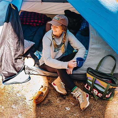 A woman sitting in the doorway of a tent.