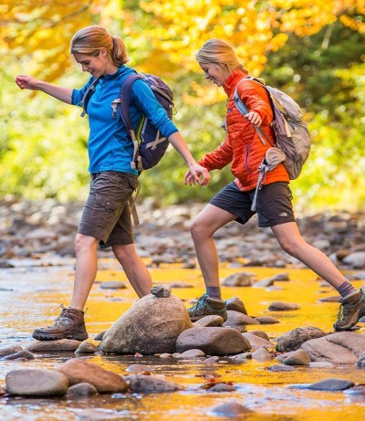 Two woman hiking across a river