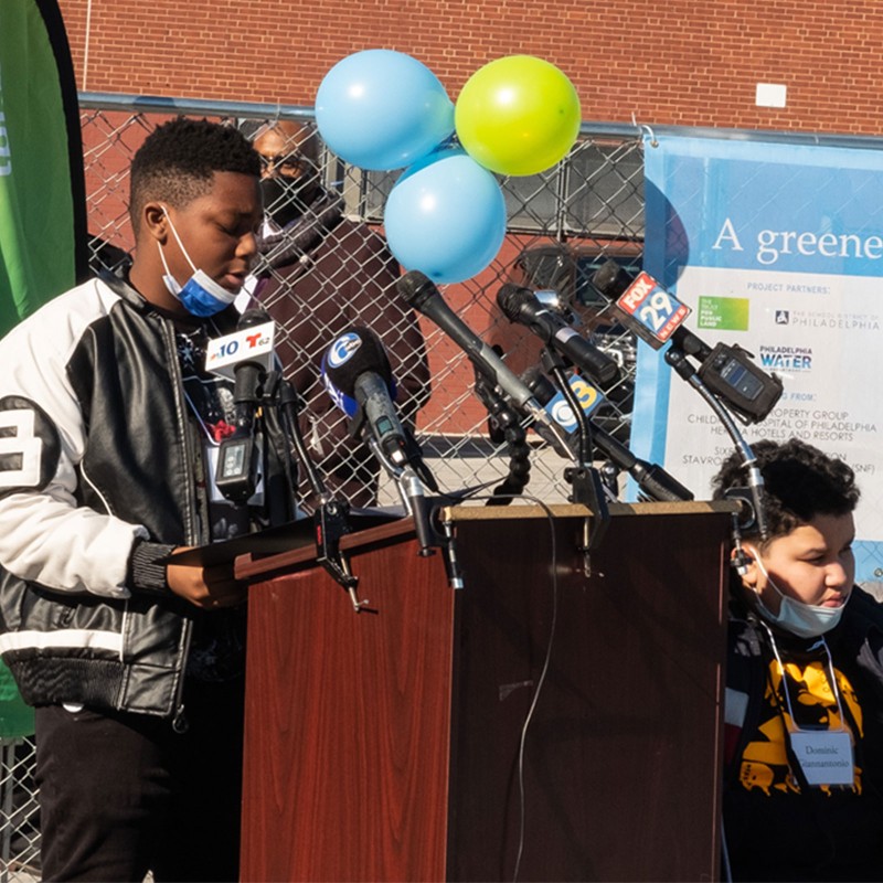 2 kids outside by a podium during a press release.
