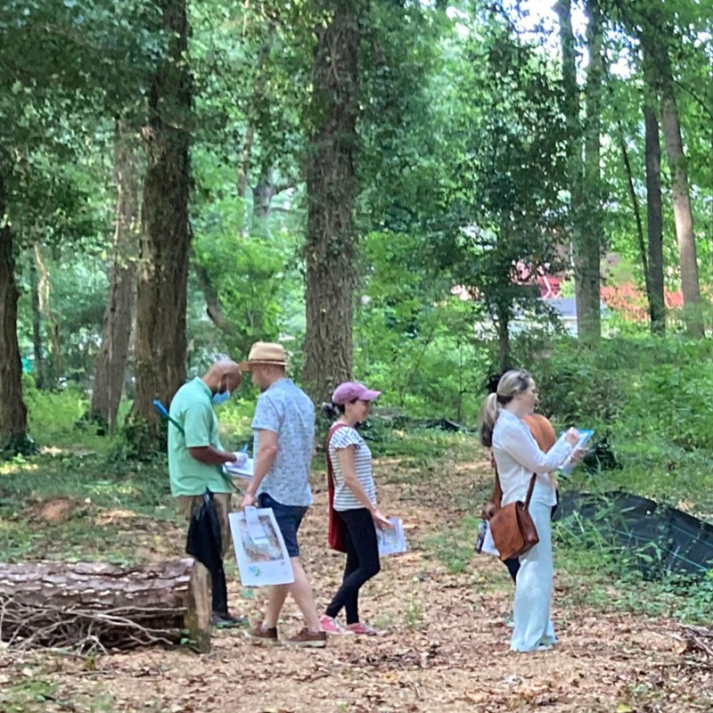 4 adults walking around on a wooded trail under construction.