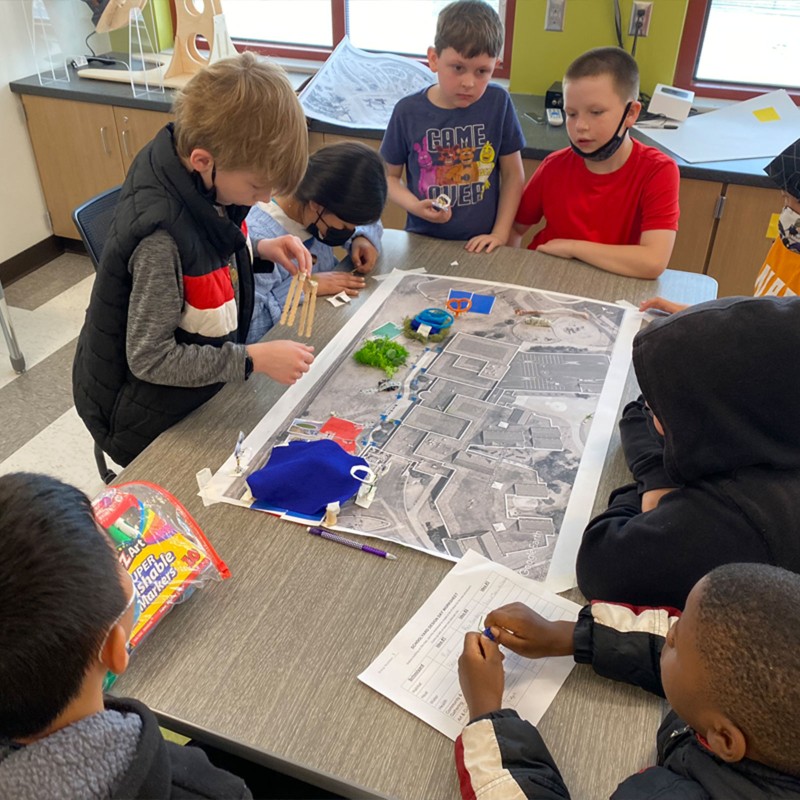 Children sitting around a table in a classroom working on a project together.