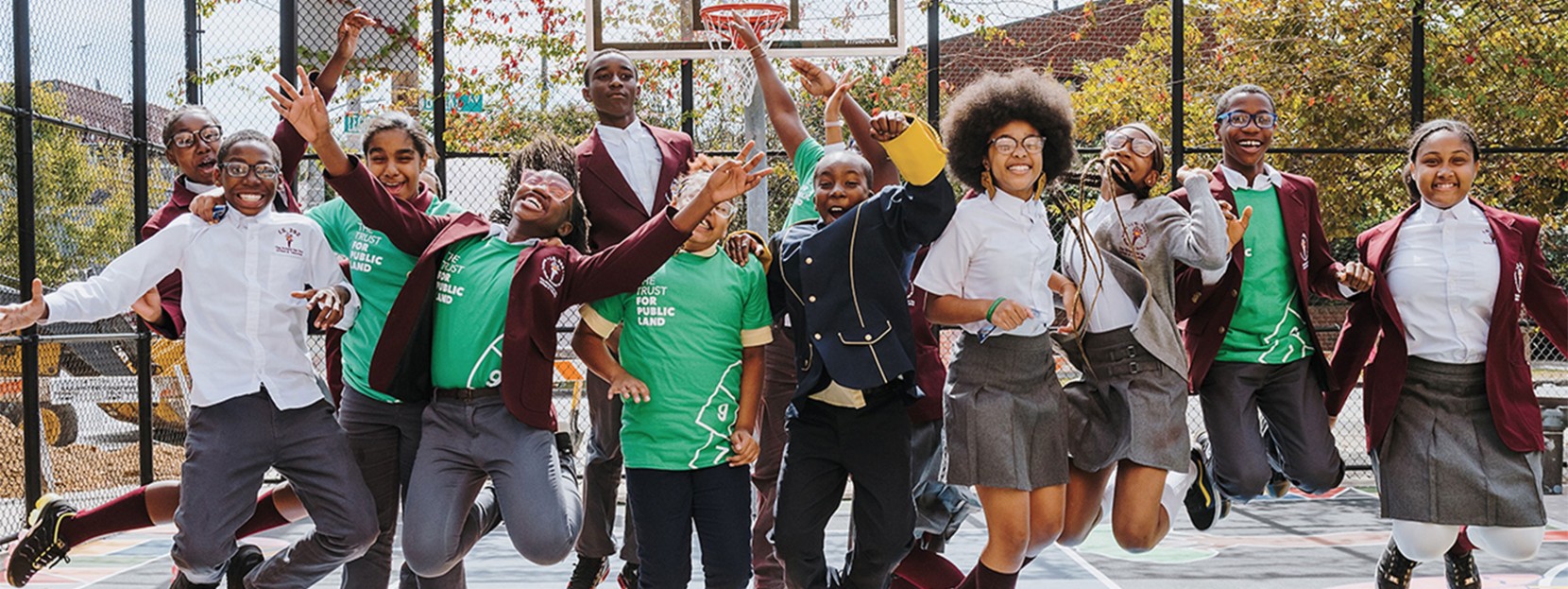 A group of teenagers in school uniforms smiling and jumping