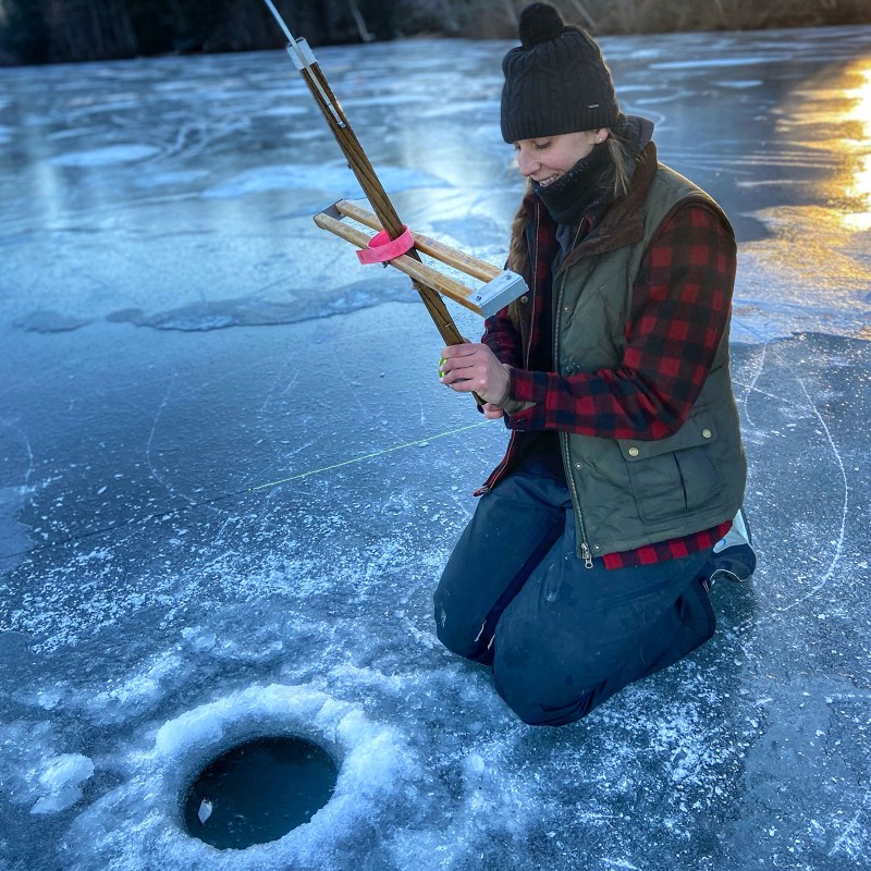 A woman getting ready to set a line in an ice-fishing hole.