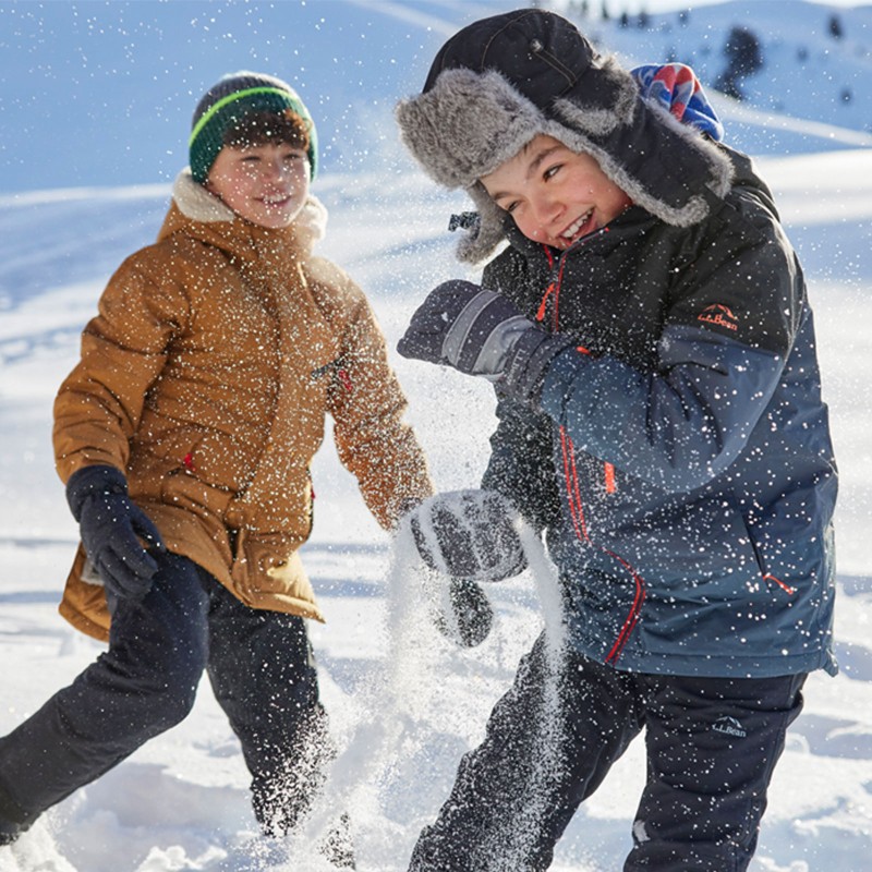 Two laughing kids having a snowball fight.