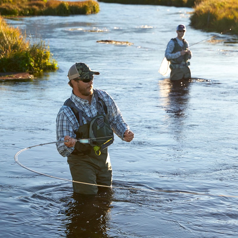 Two men standing in water and fishing