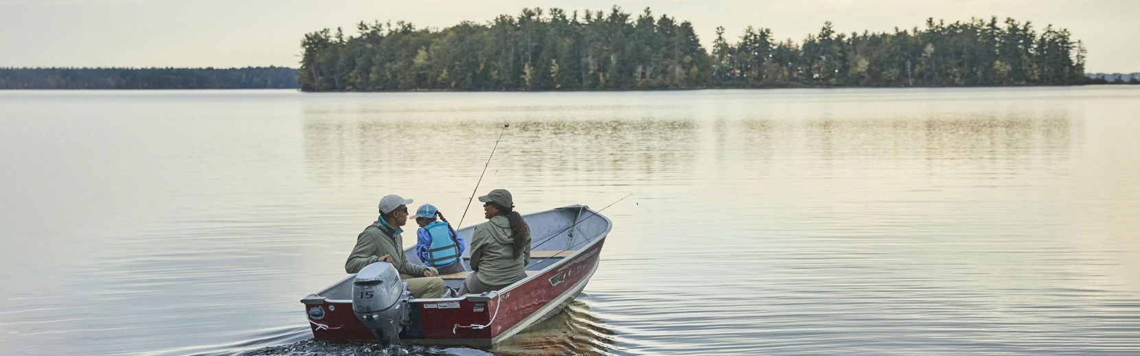 A family heading out to fish on a lake in their boat.