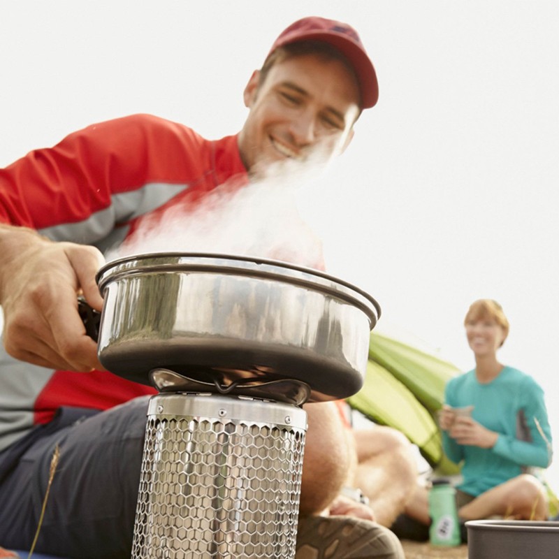 A man boiling water outside over a camp stove.