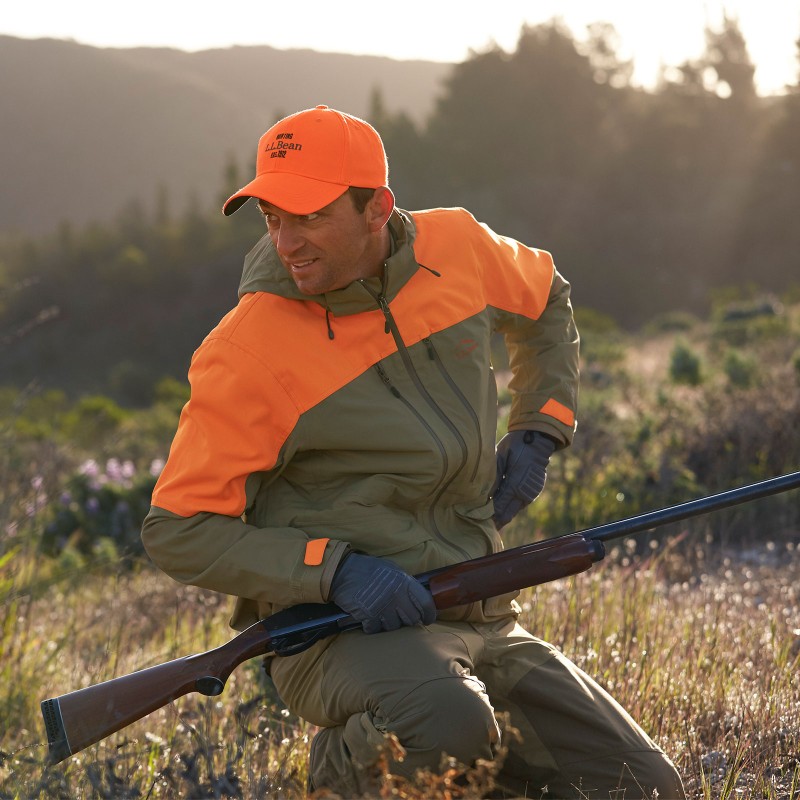 A hunter .kneeling in a field.