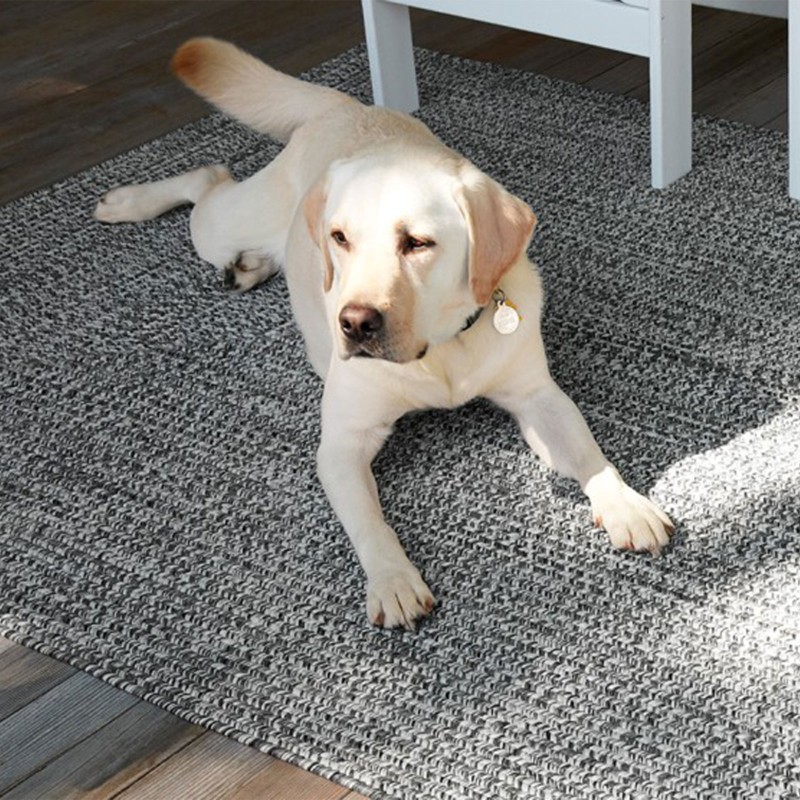A dog lying on an outdoor rug on a porch