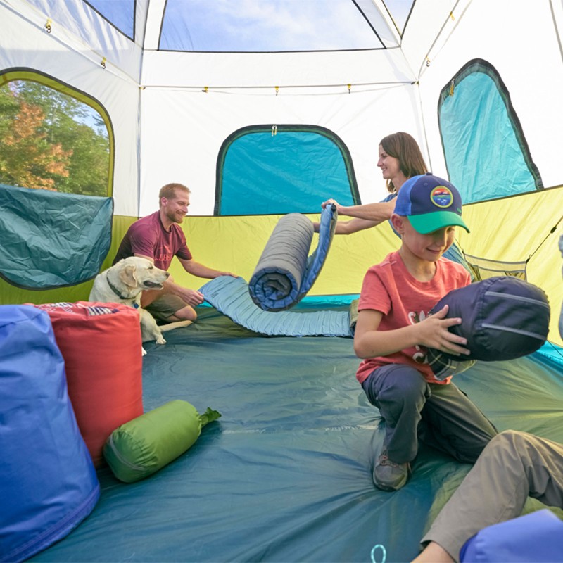 A family laying out sleeping bags in a tent.