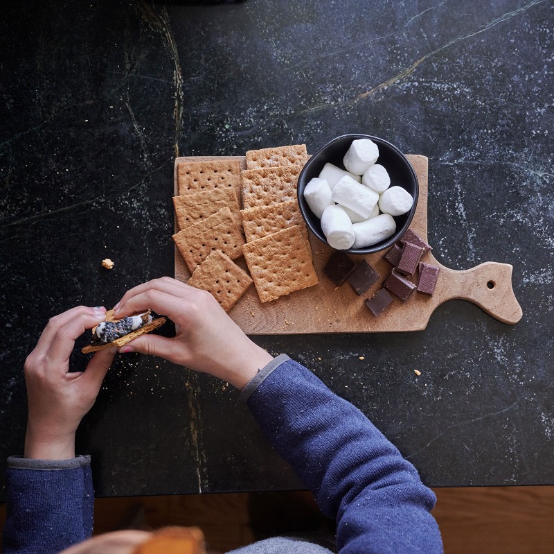 Overhead view of a child's hands constructing a s'more.