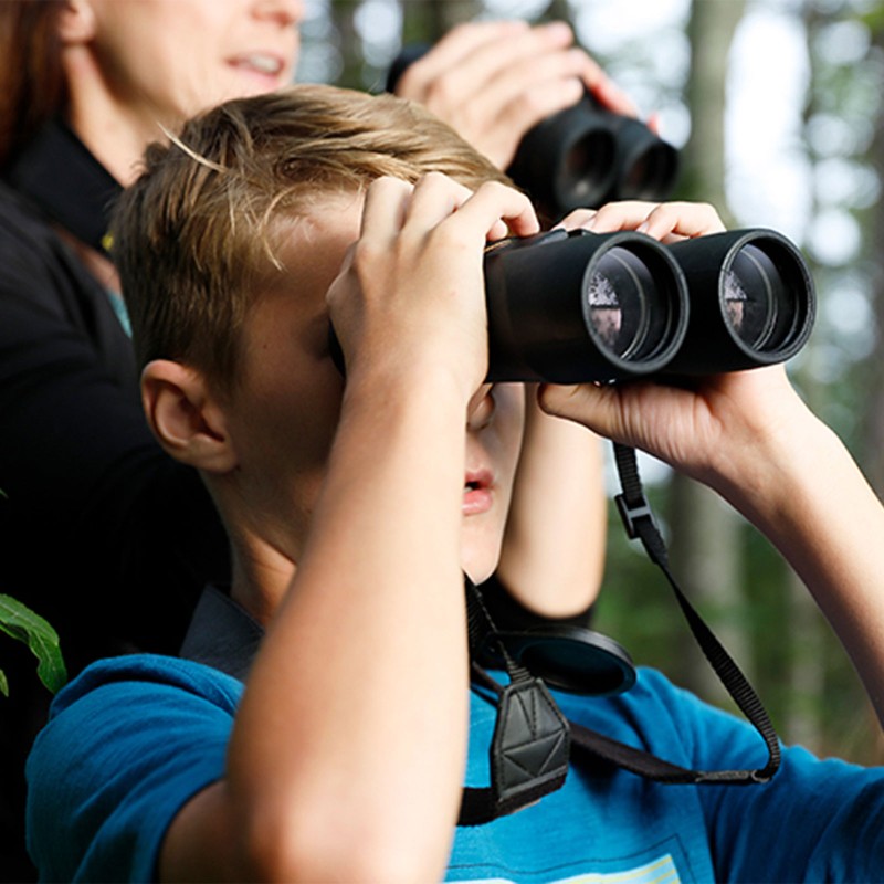 Close-up of parent and child looking through binoculars.