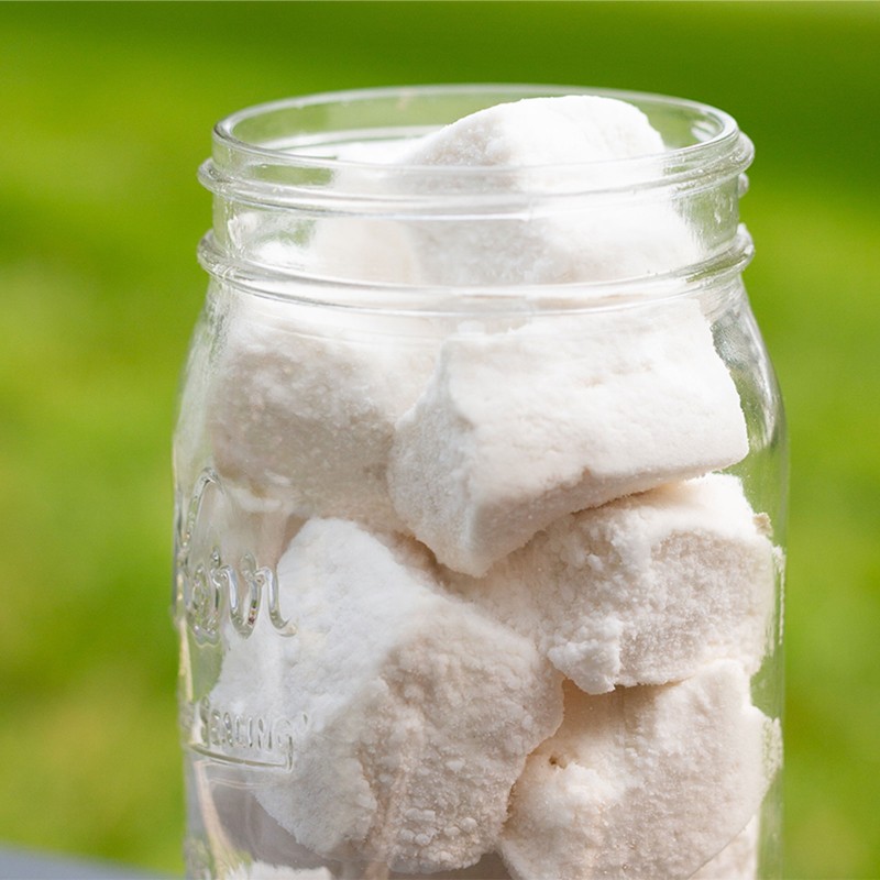 A jar of powder sugar dusted marshmallowa