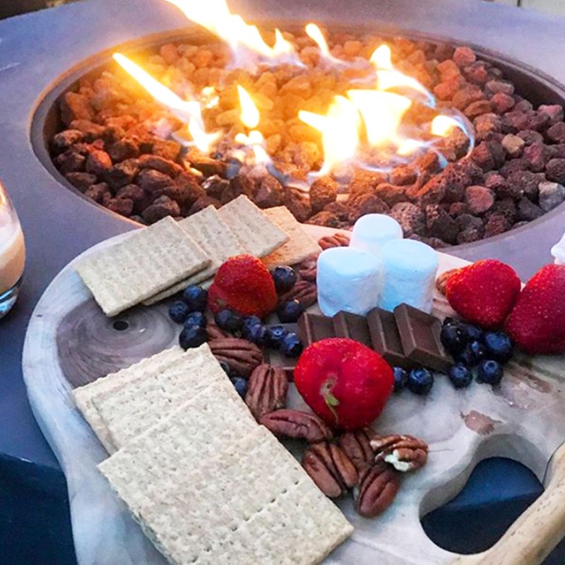 Cookies, marshmallows, blueberries, raspberries near a firepit.