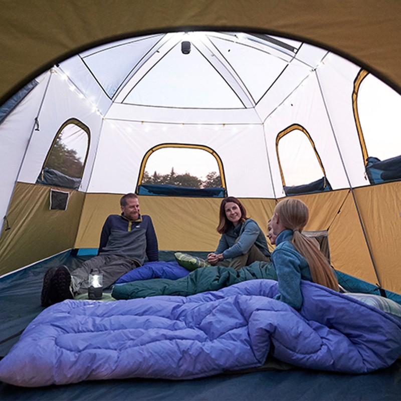 Happy family of 4 sitting and talking inside their tent.