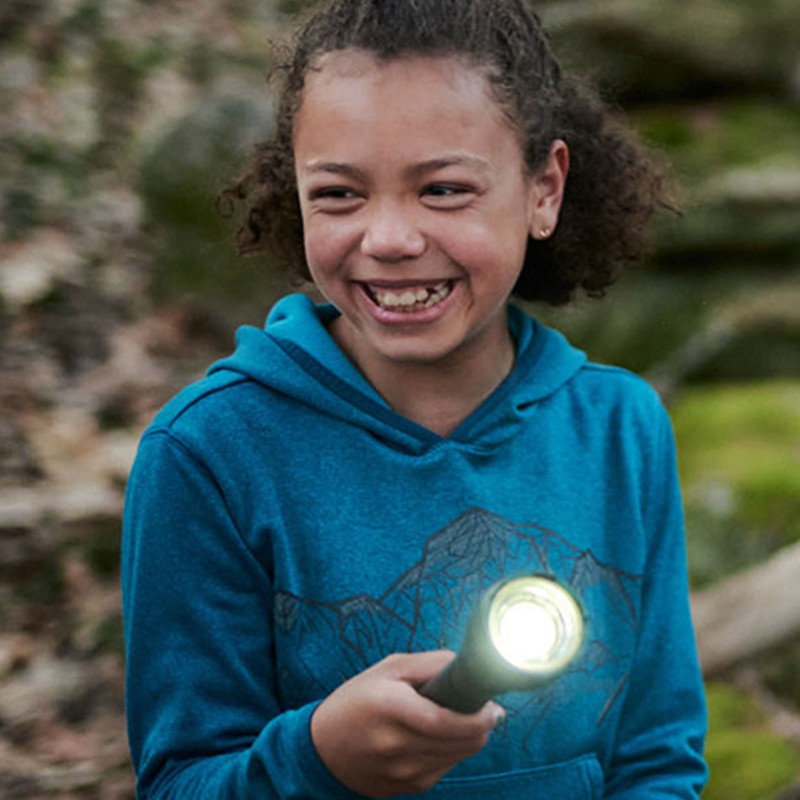 Smiling girl outside with a flashlight.